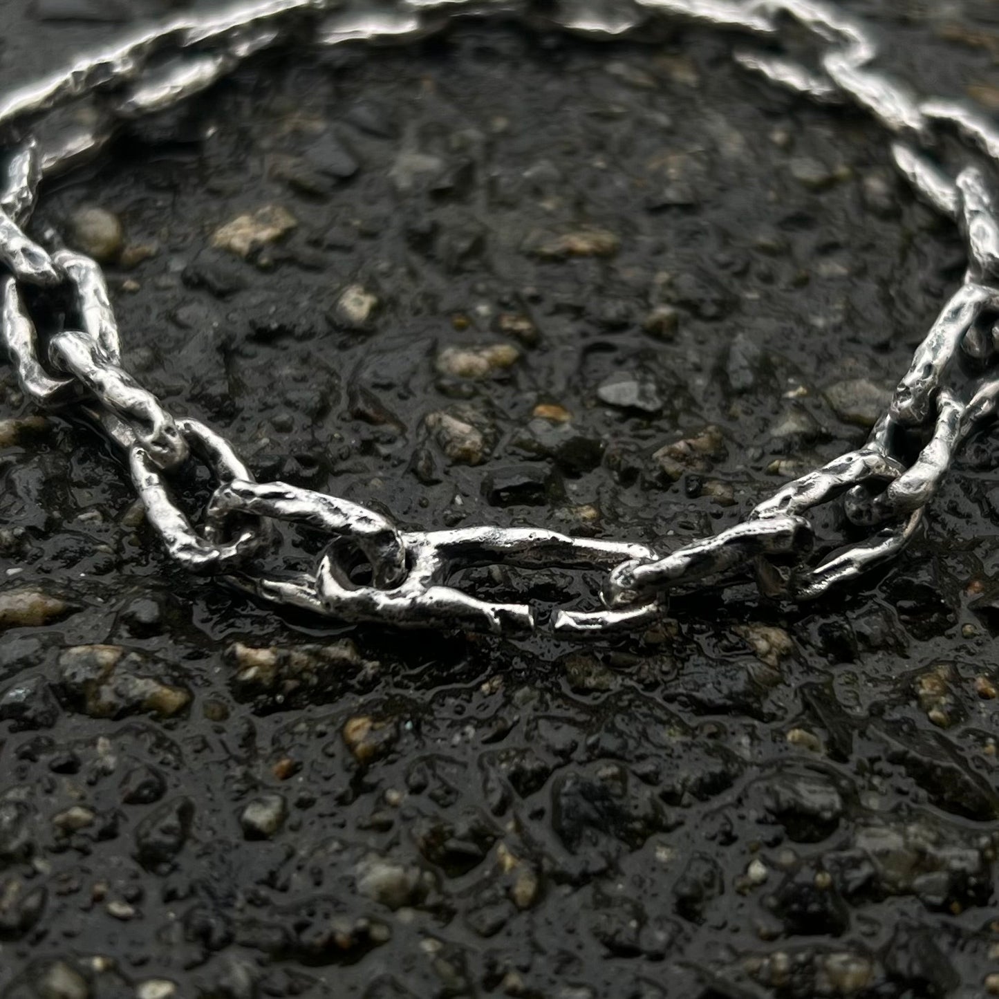 Gros plan sur les maillons irréguliers d’un bracelet chaîne artisanal en argent massif texturé