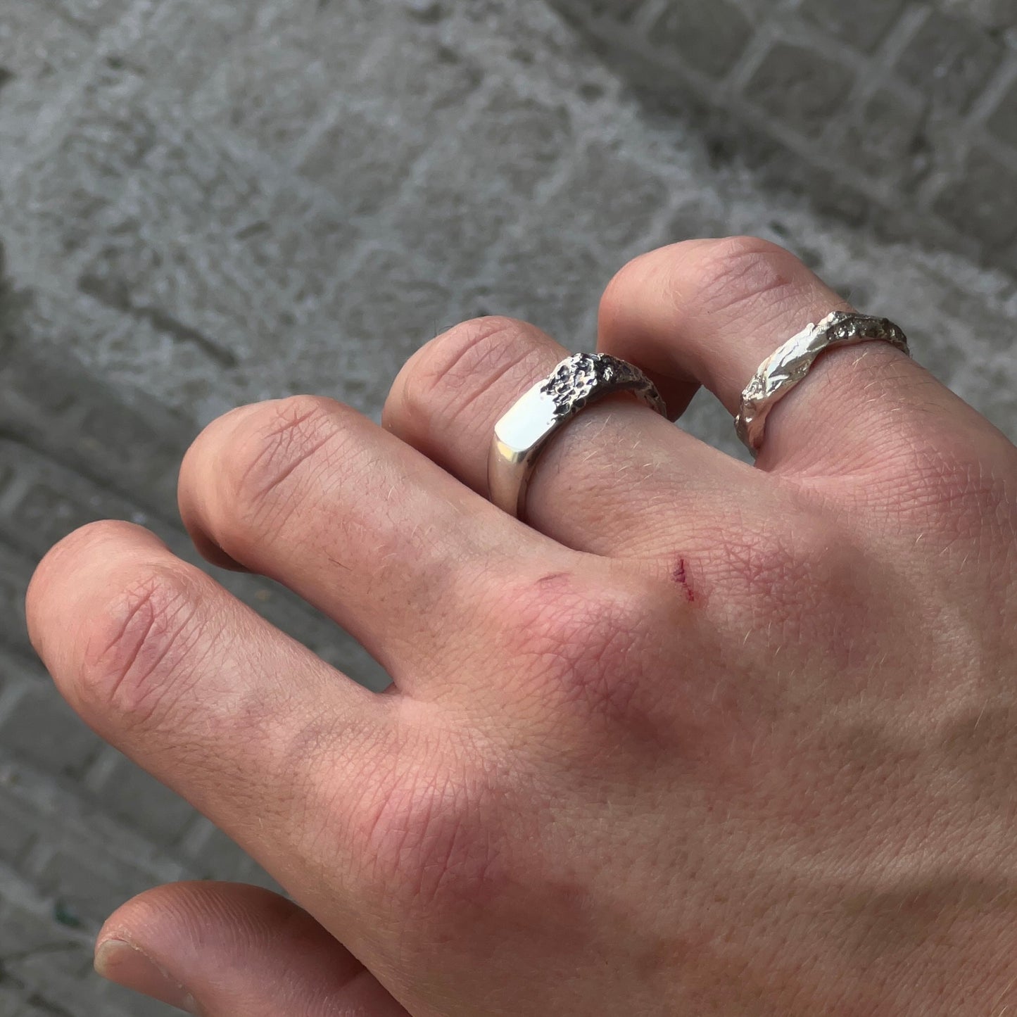 Image d’une bague brute en argent pour homme et femme, façonnée par fonte au sable dans un atelier d’artisan créateur. Ce bijou unisexe à la texture naturelle incarne un style puissant et minimaliste, à contre-courant du bijou traditionnel.