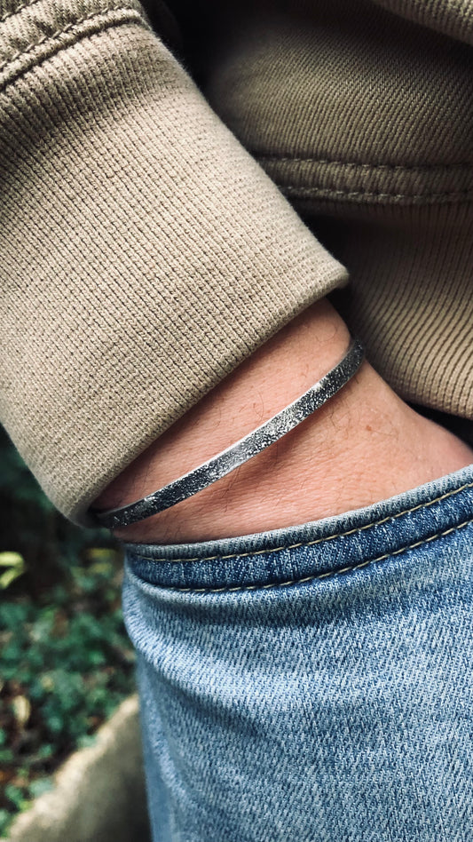 Bracelet jonc volcanique jonc en argent avec texture pour homme en argent porté sur un mannequin bijoux patiné de couleur argent et noir 