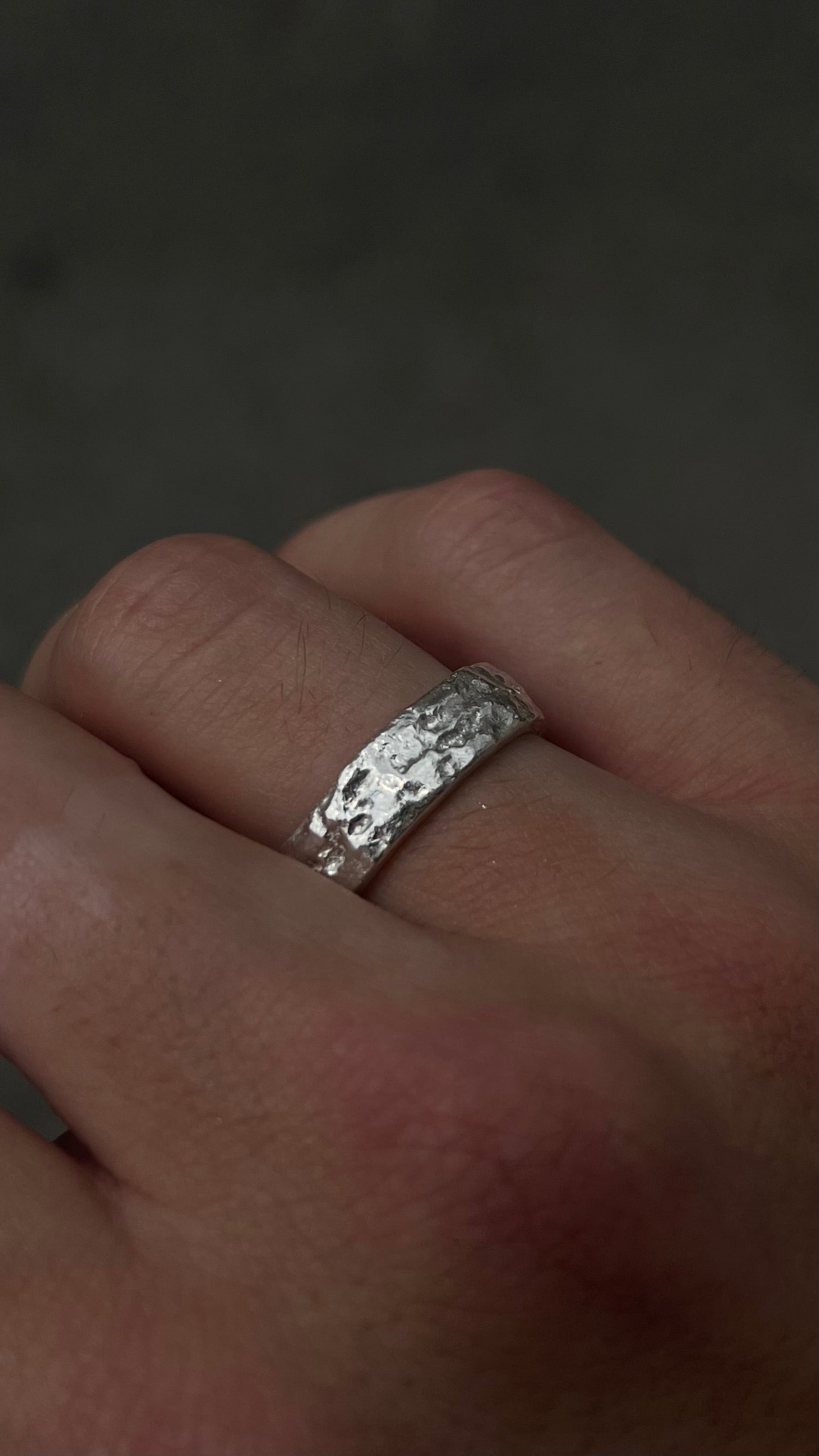 Bague artisanale en argent 925 portée à la main, aux textures brutes inspirées de la roche.
