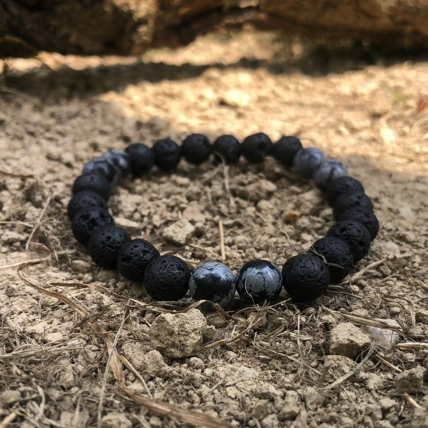 Bracelet élastique en perles de 8 mm, disponible en trois variantes : Pierre de Lave et Onyx Noir, Obsidienne Flocon de Neige et Pyrite. Ces bracelets artisanaux, disponibles en tailles S, M et L, présentent des effets de matière uniques et une identité forte, reflétant l'élégance et l'authenticité de la collection Fonte