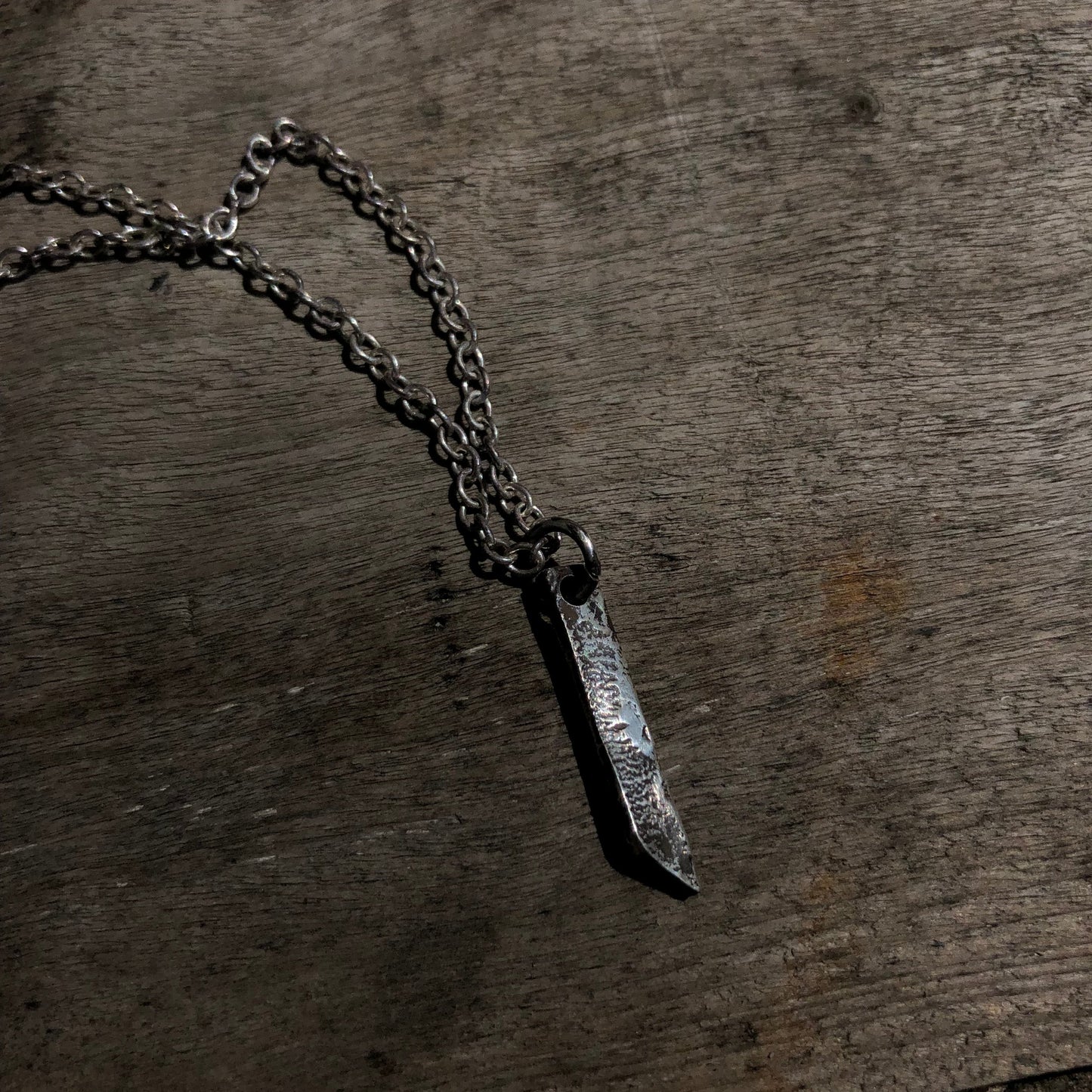 Collier en argent massif avec pendentif rectangulaire, doté d'une texture brute obtenue par la technique de réticulation, un bijou artisanal au style distinctif.