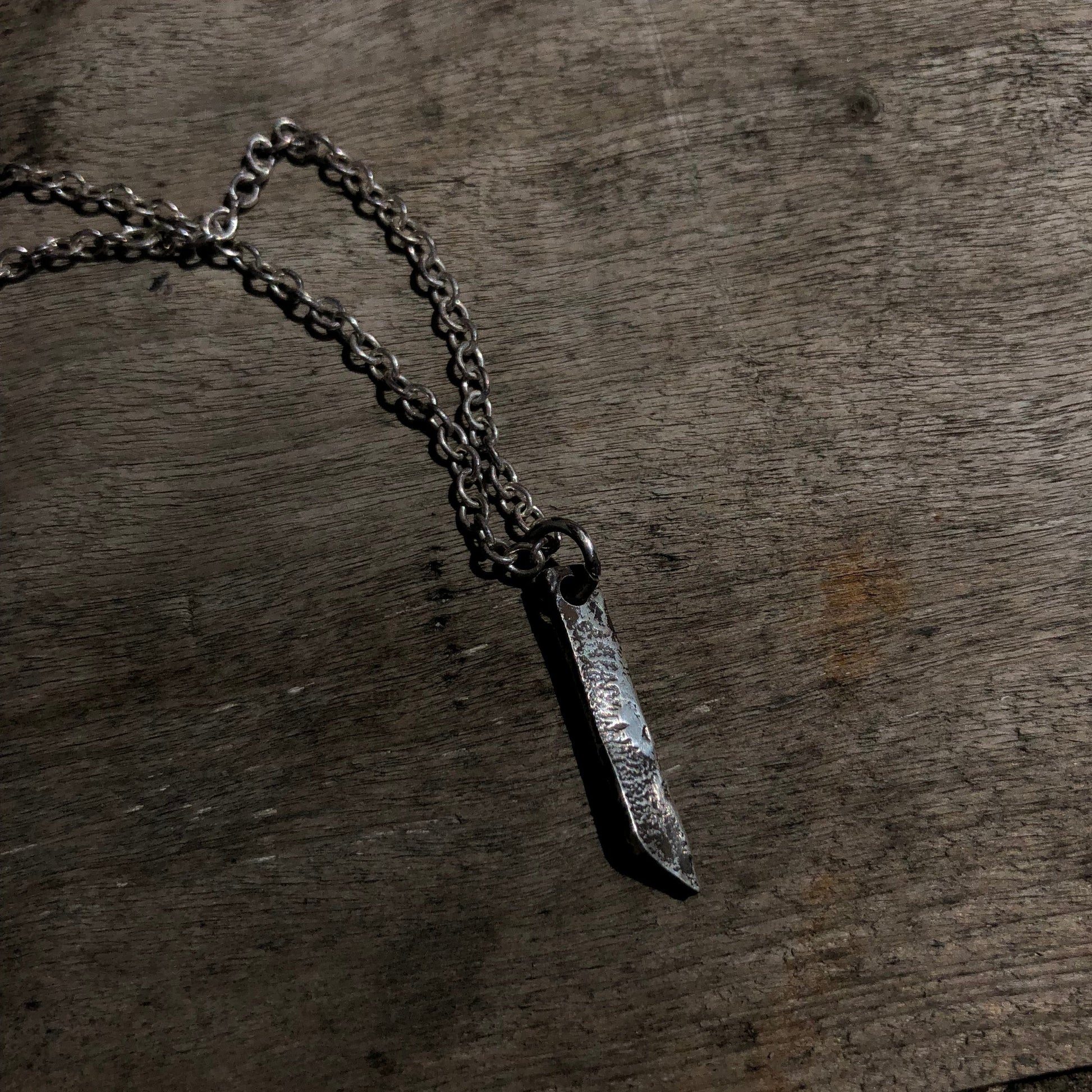 Collier en argent massif avec pendentif rectangulaire, doté d'une texture brute obtenue par la technique de réticulation, un bijou artisanal au style distinctif.