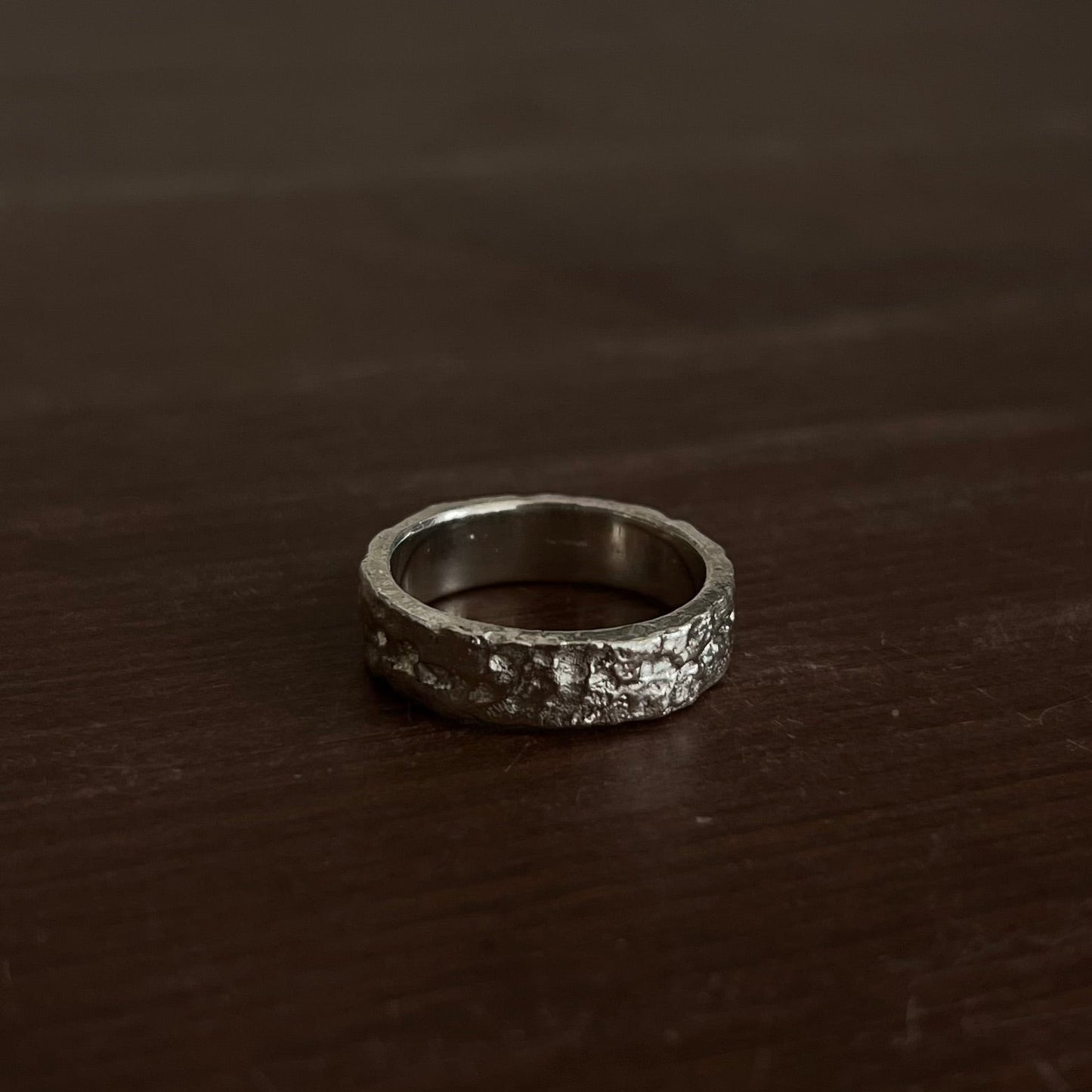 Gros plan sur la texture minérale de la bague en argent 925 réalisée grâce à la fonte au sable.