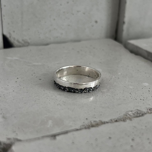 Bague argent 925 posée sur du béton, vue de dessus