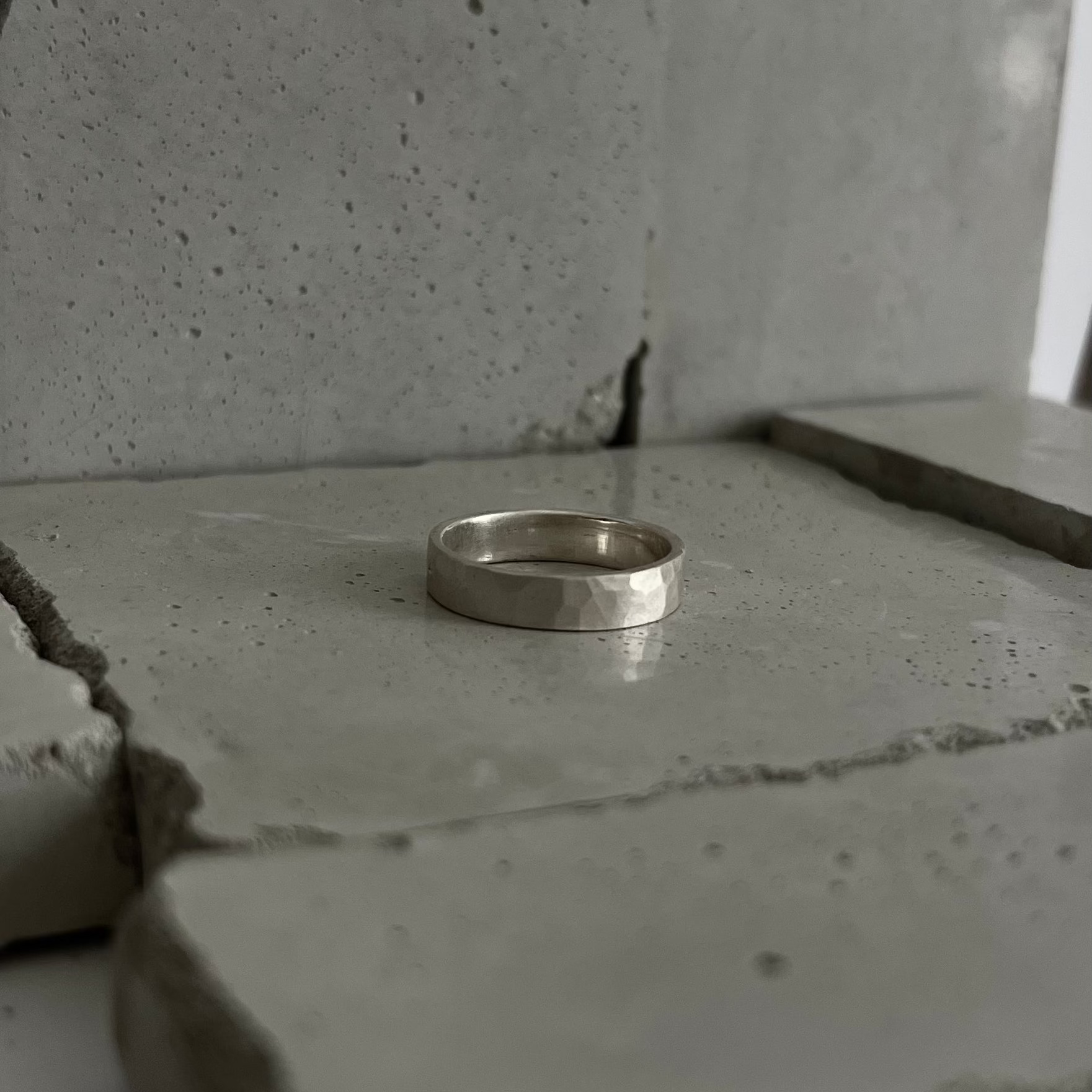 Anneau forgé en argent 925 martelé, posé sur une pierre sombre
