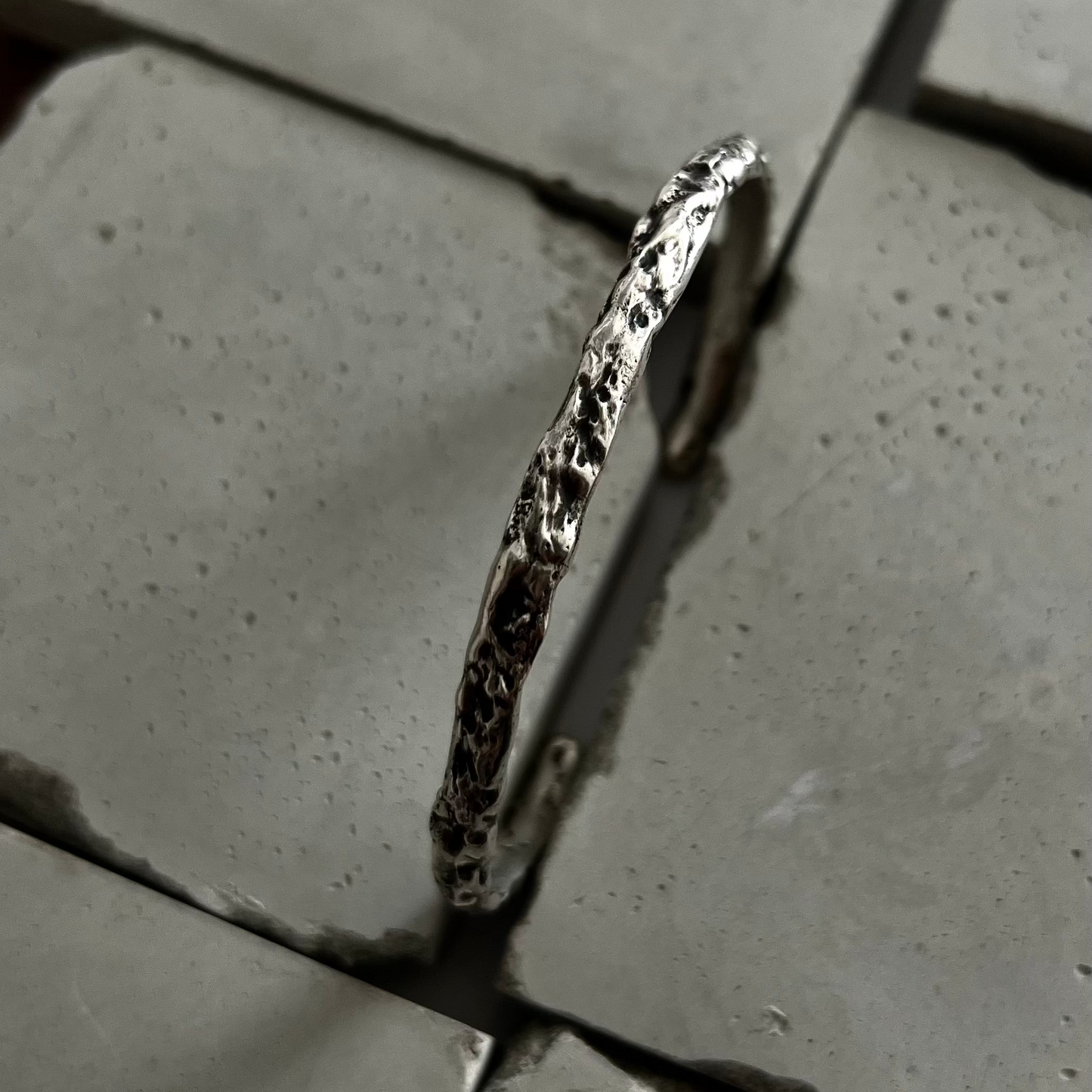 Gros plan sur les creux et les reliefs d'un jonc en argent