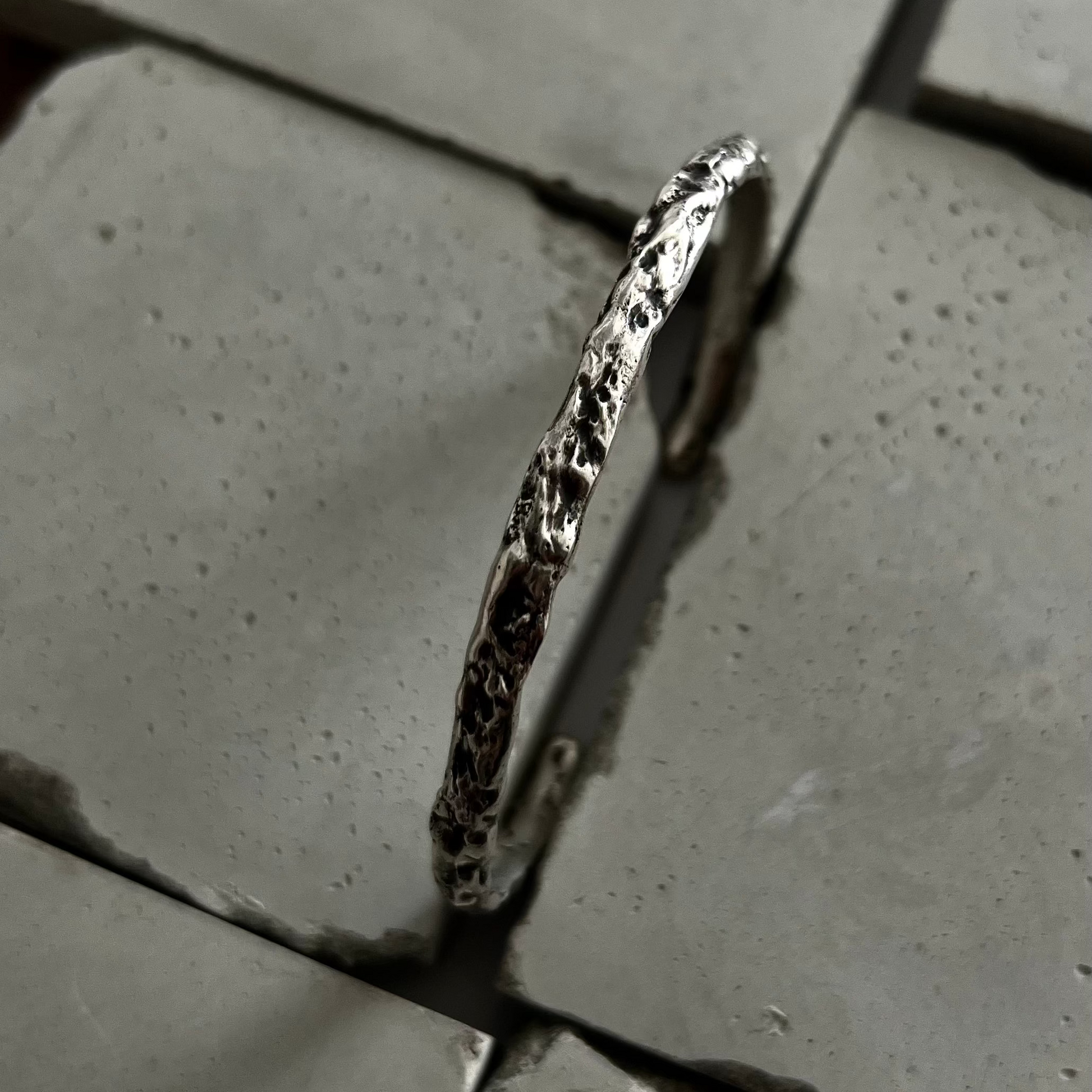 Gros plan sur les creux et les reliefs d'un jonc en argent