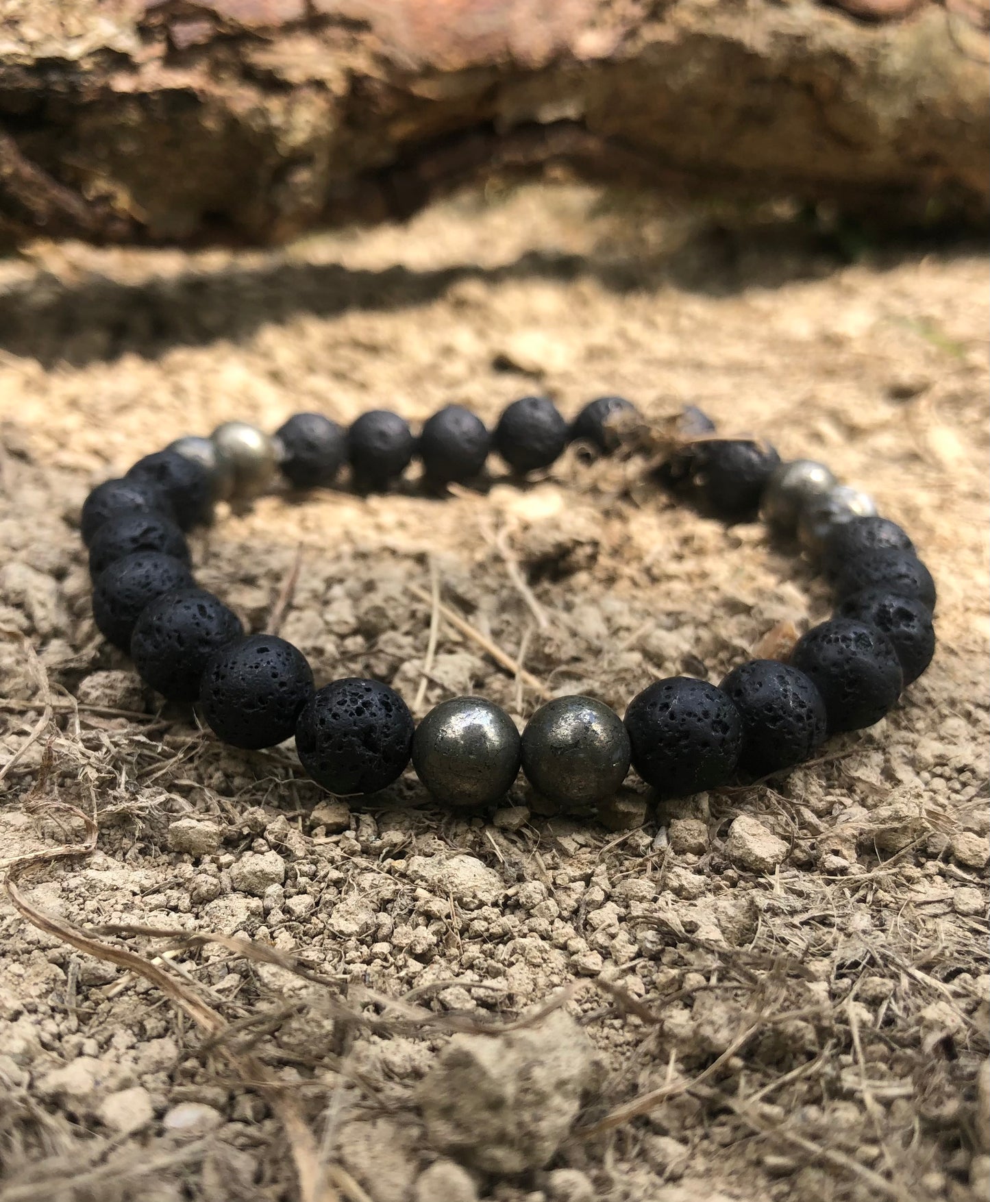 Bracelet élastique en perles de 8 mm, disponible en trois variantes : Pierre de Lave et Onyx Noir, Obsidienne Flocon de Neige et Pyrite. Ces bracelets artisanaux, disponibles en tailles S, M et L, présentent des effets de matière uniques et une identité forte, reflétant l'élégance et l'authenticité de la collection Fonte.